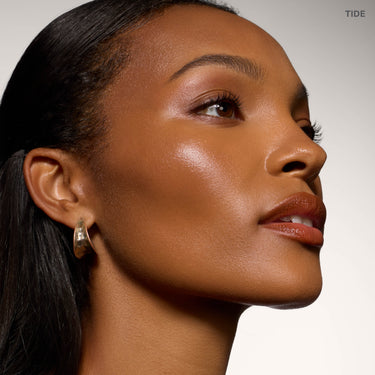 {Tide}  Model wearing Morphe Complexion Boost Peptide Bronzing Serum in Tide, showing a dewy, bronzed complexion